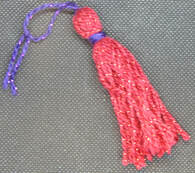 A red tassel with a purple tie lying diagonally on a black background