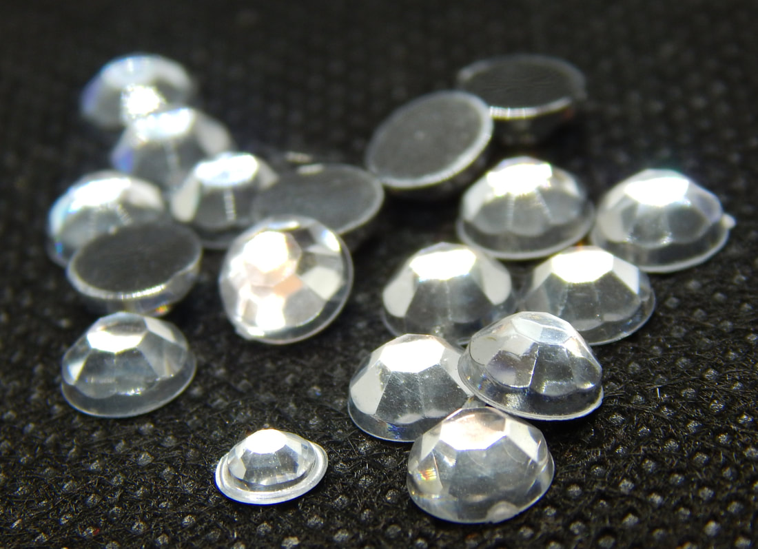 A pile of silver and clear gems on a black background
