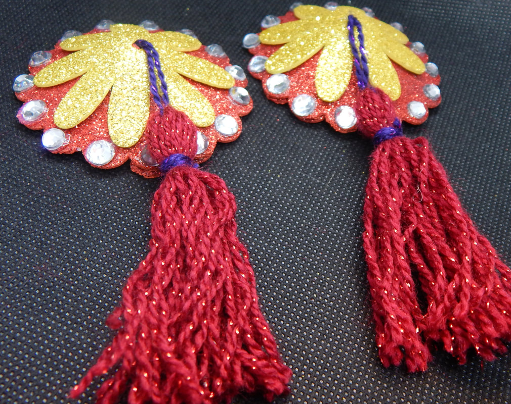 A pair of red and silver pasties with red and purple tassels on a black background