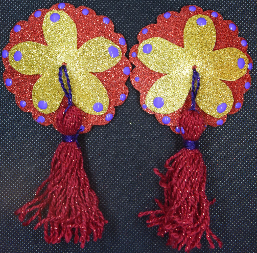A pair of pasties (nipple covers) with a red glitter round background with scallops, a gold glitter flower shape on top, Purple dots on each scallop as well as the edge of the petals, and a purple and red tassel coming from the center