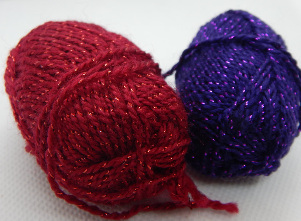 Two small balls of yarn, one is red and the other purple